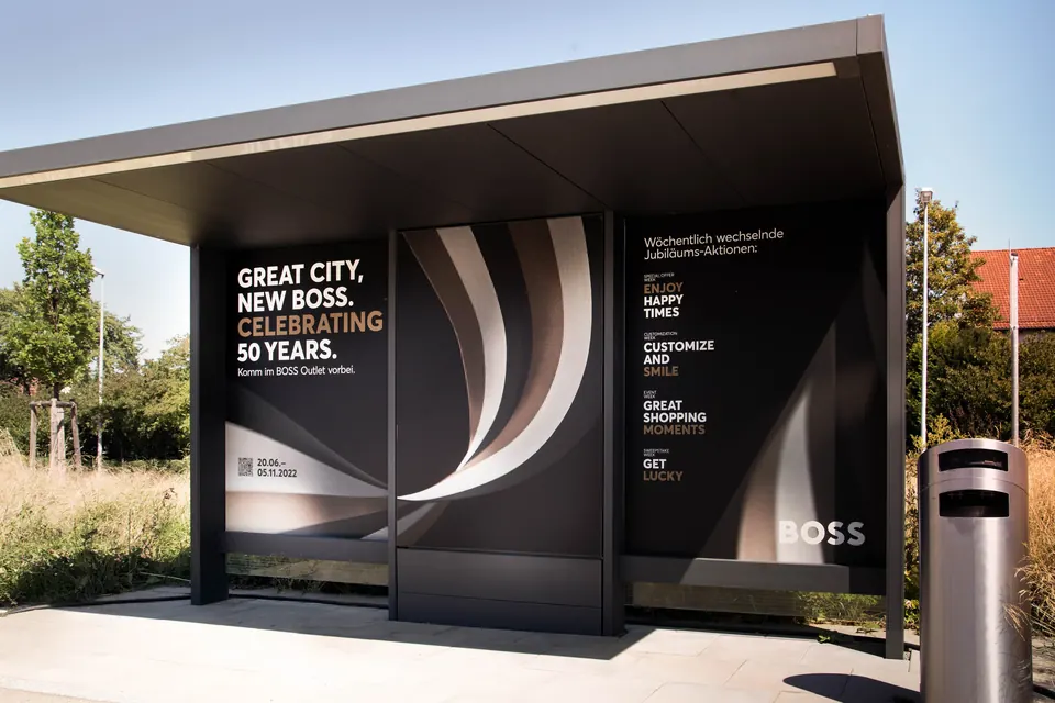 Plakat „Great City, New Boss. Celebrating 50 Years.“ an einer Haltestelle in Metzingen