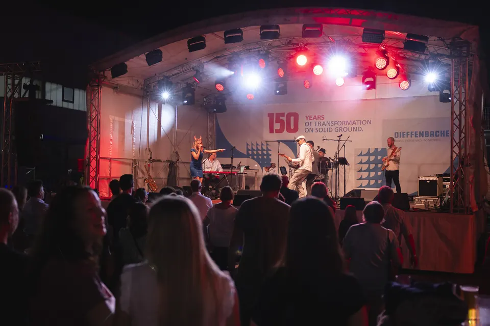 Band auf der Bühne beim Jubiläumsfest von Dieffenbacher, dahinter das Leitmotiv „150 years of transformation on solid ground“