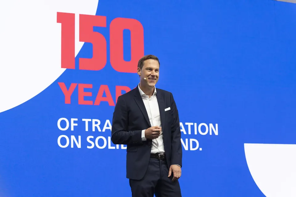 Dieffenbacher-Geschäftsführer auf der Bühne vor dem Jubiläums-Leitmotiv „150 years of transformation on solid ground“