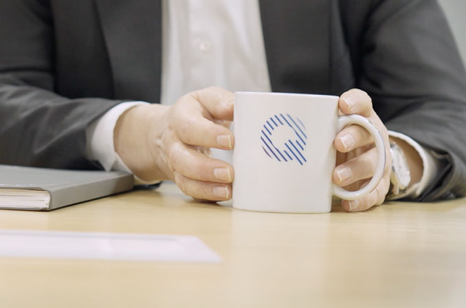 Mitarbeiter hält Tasse bedruckt mit Bosch Quality Principles Logo