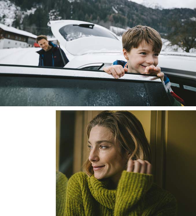 Mann mit seinem Kind am Auto und eine Frau sieht aus dem Fenster