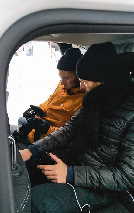 Zwei Männer sitzen im Auto und schauen sich Bilder im Kamera-Display an